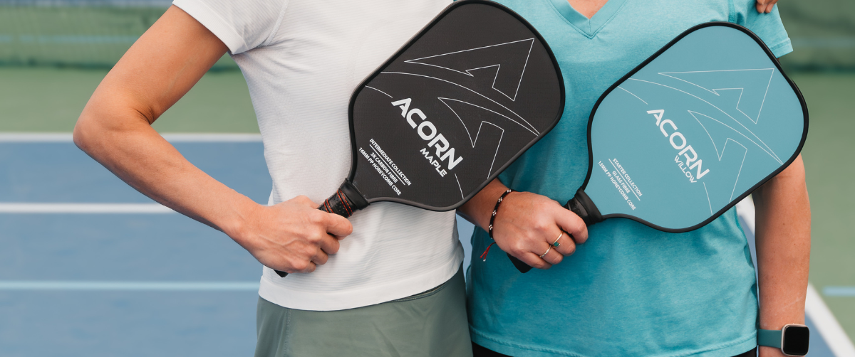 Two people holding black and blue pickleball paddles